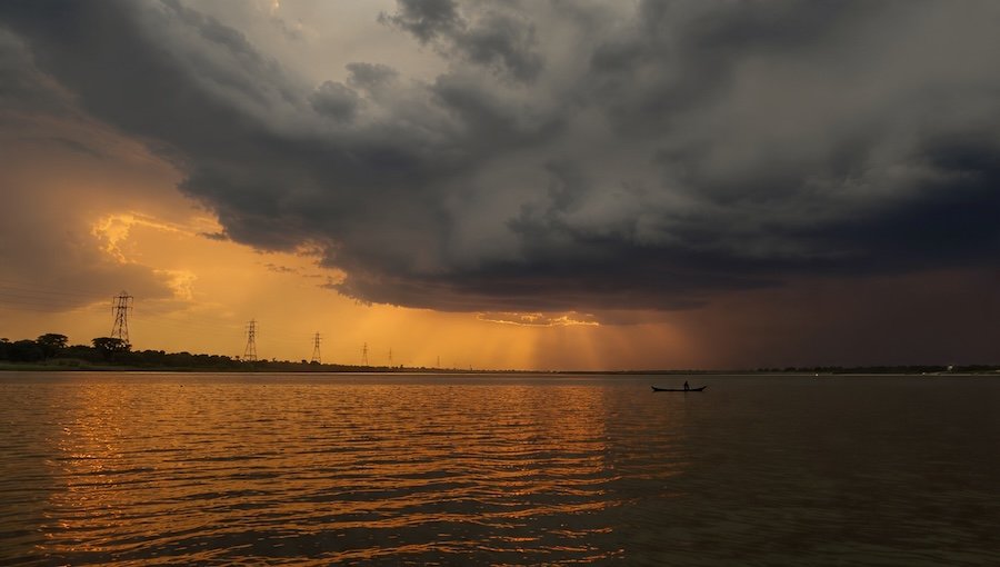 AI-generated image by Meta AI using Gemini’s prompt, showing a different interpretation of the Damodar River sunset and boat scene.